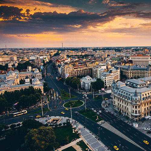 An aerial view of Bucharest, Romania, at sunset, featuring the Palace of the Parliament and the city's historic center